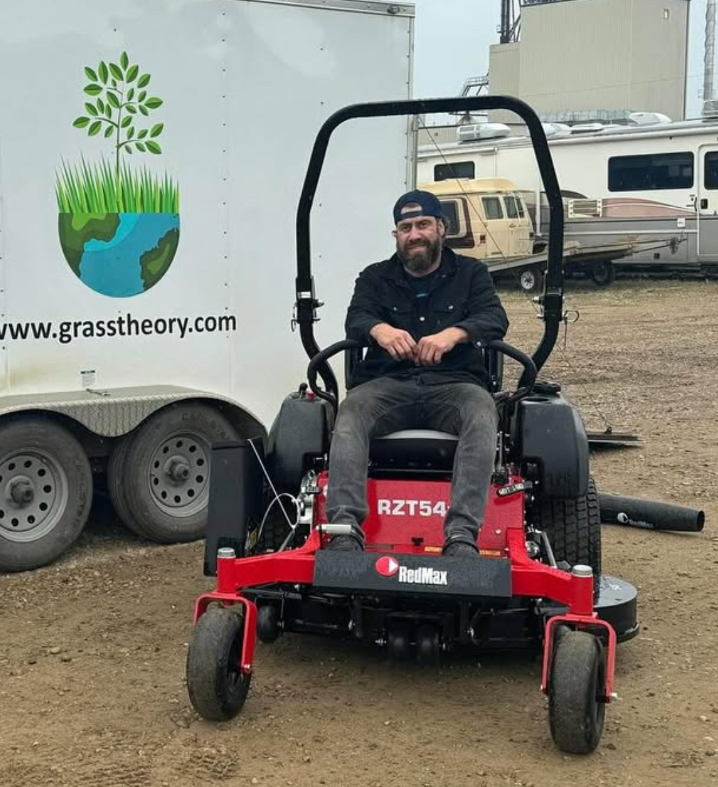 Scott McClocklin, owner of Grass Theory, on his RedMax zero-turn mower in front of the Grass Theory work trailer